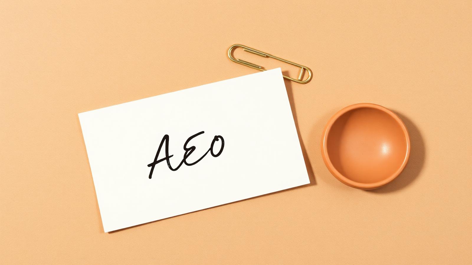 Cream card with handwritten AEO beside a brass paperclip and terracotta dish, representing AEO for B2B marketing